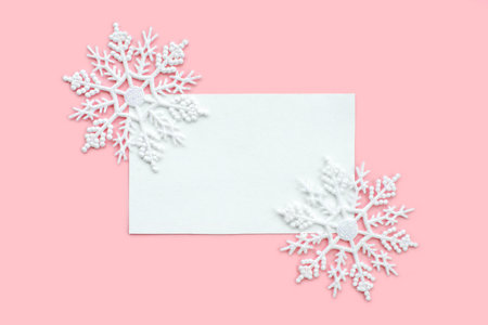 White paper card decorated with snowflakes on pink background. New Year, Christmas and winter...