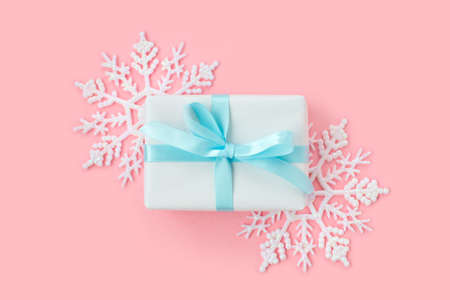 White gift box decorated with snowflakes on pink background. New Year, Christmas and winter concept. Flat lay, top view.の写真素材