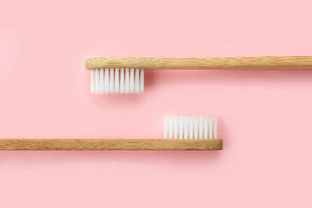 Two bamboo toothbrushes on pink background. Dental and healthcare concept. Top view, flat lay.の写真素材