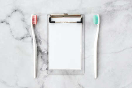 Set of pink and turquoise blue toothbrushes and empty note on marble background. Dental and health care concept. Top view, flat lay. Free copy space.の写真素材