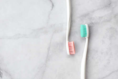 Two toothbrushes with pink and turquoise blue bristle on marble background. Dental and health care concept. Top view, flat lay. Free copy space.の写真素材