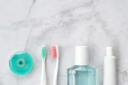 Set of pink and turquoise blue toothbrushes, toothpaste and other tools on marble background. Dental and health care concept. Top view, flat lay. Free copy space.の写真素材