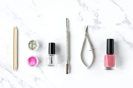 Set of various manicure and pedicure tools and accessories on white marble background. Top view.