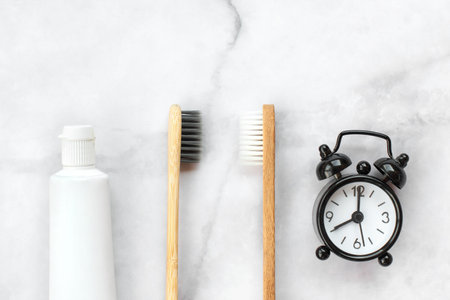Set of eco-friendly toothbrushes and clock on marble background. Dental and healthcare concept. Top view, flat lay.の写真素材