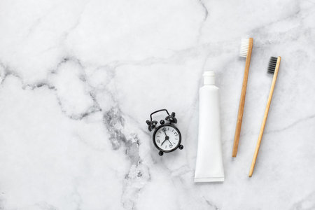 Set of eco-friendly toothbrushes, toothpaste, clock on marble background. Dental and healthcare concept. Top view, flat lay. Free copy space.の写真素材