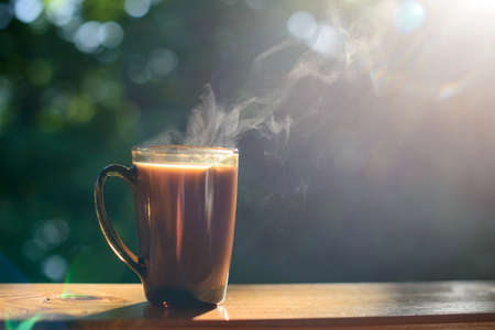 Cup of coffee and cellphone on the windowsill over blurred forest background at sunny summer day. Free copy space.の写真素材