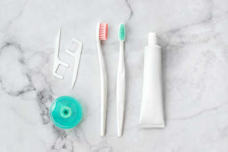 Set of pink and turquoise blue toothbrushes, toothpaste and other tools on marble background. Dental and health care concept. Top view, flat lay.の写真素材