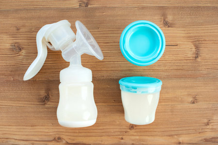 Set of breast pump and bottles with breast milk for baby on wooden background. Maternity and baby care concept. Top view. Flat lay.の写真素材
