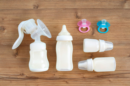 Set of breast pump and bottles with breast milk for baby on wooden background. Maternity and baby care concept. Top view. Flat lay.の写真素材