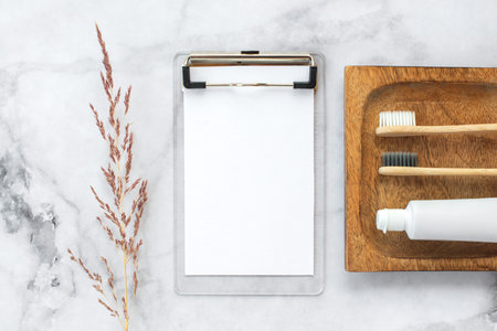 Set of eco-friendly toothbrushes, toothpaste and note free copy space and marble background. Dental...