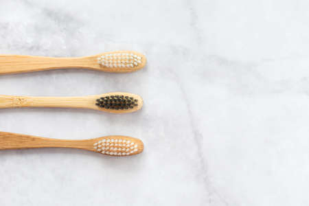 Two bamboo toothbrushes on marble background. Dental and healthcare concept. Top view, flat lay. Free copy space.の写真素材
