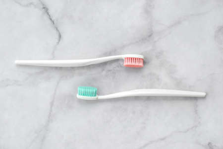 Two toothbrushes with pink and turquoise blue bristle on marble background. Dental and health care concept. Top view, flat lay.の写真素材