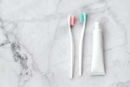 Two toothbrushes with pink and turquoise blue bristle and toothpaste on marble background. Dental and health care concept. Top view, flat lay. Free copy space.の写真素材