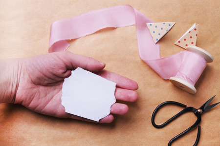 Hand made craft background. Hand with scissors, and silk ribbon. Mockup. Rustic styleの写真素材