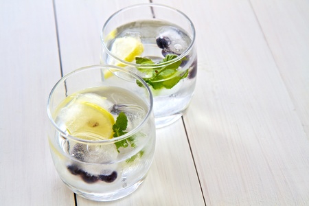 Ice cubes with fruit and mint in a glass of water with space for textの写真素材