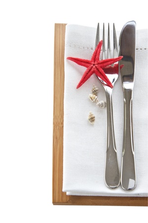 Knife and fork with napkin and starfish for a beach table setting isolated on whiteの写真素材