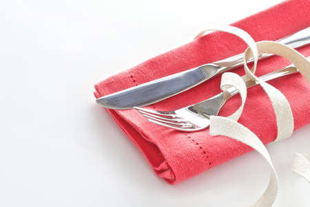 Knife and fork with tangerine napkin tied with natural ribbon and isolated on white background with place for textの写真素材