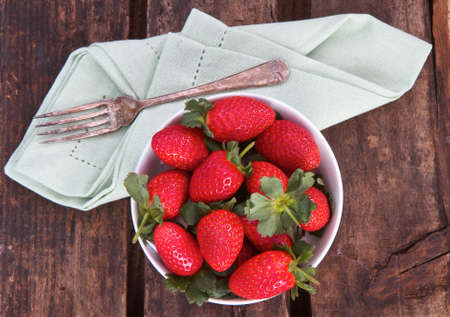 Strawberries on wooden background with vintage fork and napkinの写真素材