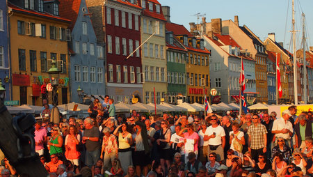 Copenhagen, Denmark - July 12, 2013: A large crowd watching live music and dancing at sunset in the...