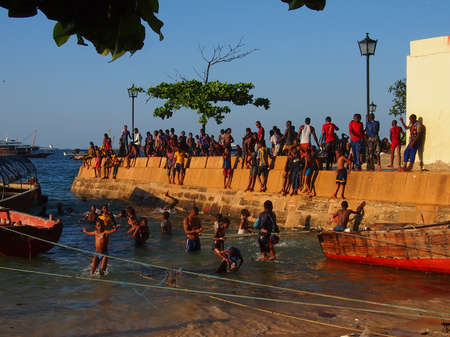 Stone Town, Zanzibar, Tanzania - November 27, 2015: Locals play and jump into the sea as the sun sets. There were hundreds of people jumping in along the entire stretch of sea front every evening.のeditorial素材