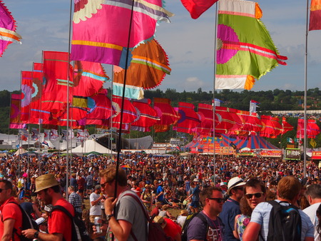 Pilton, United Kingdom - June 26, 2015: Music festival crowd in the sun underneath colourful flagsのeditorial素材