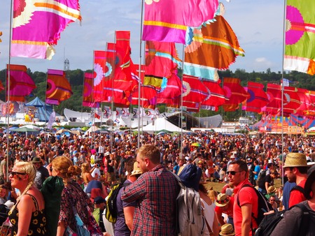 Pilton, United Kingdom - June 26, 2015: Music festival crowd in the sun underneath colourful flagsのeditorial素材