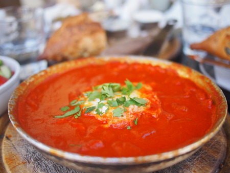 The traditional Israeli breakfast of Shakshuka. It is baked with tomatoes, onions, peppers, paprika, eggs and served with a whole loaf of sourdough bread.の写真素材