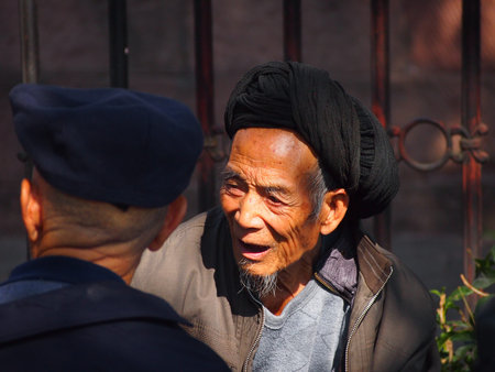 Fenghuang, China - 18 October, 2016: An elderly Chinese man chatting with friends in Fenghuang town squareのeditorial素材