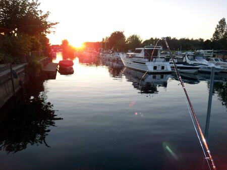 Sunset in harbour with fishing rod and boatsの写真素材