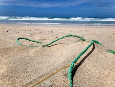 Still life on beach, rope, feather, sand, sea and skyの写真素材