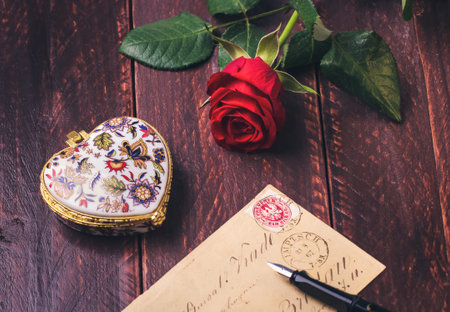 Red rose on an old love letter concept on wood table.