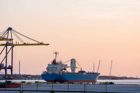 Container ship With cranes for loading goods in the port in the eveningの写真素材