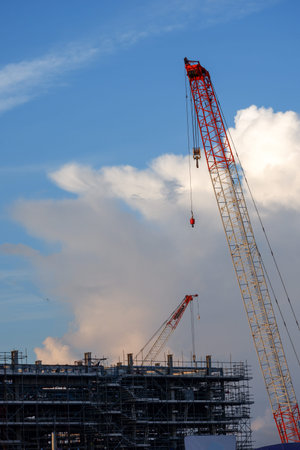 Construction tower crane The crane is surrounded by scaffolding with beautiful clouds in the...