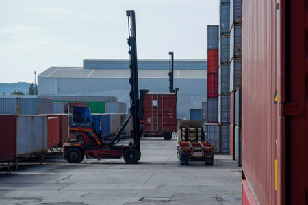 Forklift handling container boxes loaded onto truck in shipping yard with container background, logistics industry concept.の写真素材