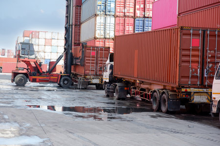 A container forklift sits behind a stack of containers.の写真素材