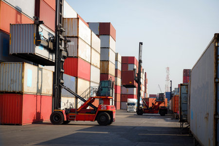 Container forklift forklift in shipping yard with stack of colorful containers, copy space background, logistics, import, export cargo, freight forwarder and transportation industry concept.の写真素材