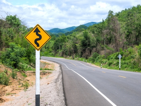 Curvy road sign to the mountain in rural areaの写真素材