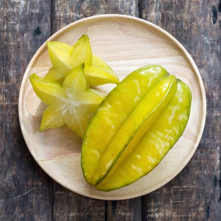 Star apple, slice, place on wooden dish, wooden floorの写真素材