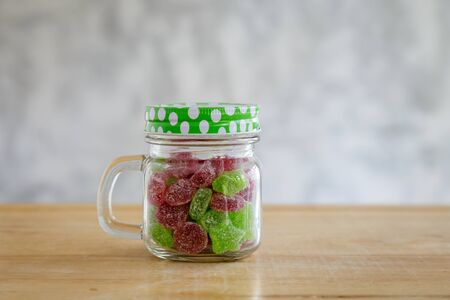Gummy candies in a glass jar on wooden table with grey background.の写真素材