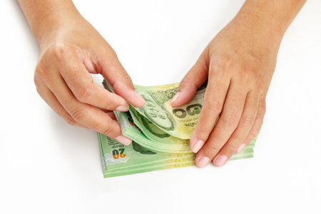 Close up hands counting thai baht money on white background.