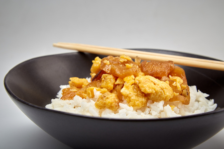 Close up view of Stir fried salted turnip with egg served with cooked rice in a dark bowl , Simple Thai food, selective focus.の写真素材