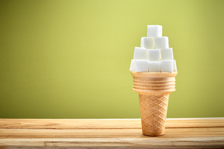 Sugar cubes in wafer cone on wooden with green background, health and sugar consumption conceptの写真素材