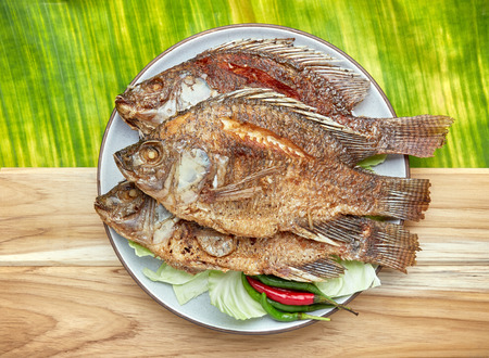 Fried fish with cabbage and chili on white plate over rustic background, Top viewの写真素材