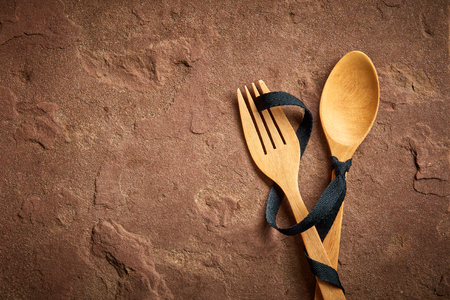 Wooden spoon and fork tied with a black ribbon on sandstone, top viewの写真素材