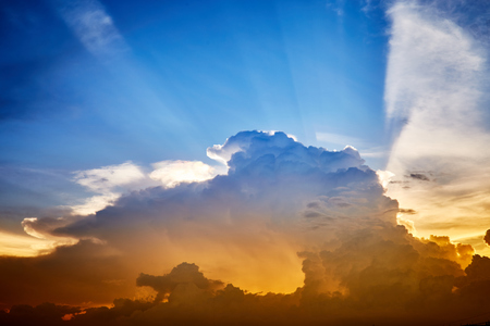 Evening sunset sky with light rays shine through the cloudsの写真素材