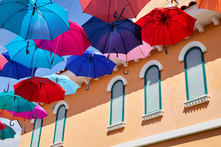 Multicolor umbrellas hanging in the sky over the street in front of the building, Street decorationの写真素材