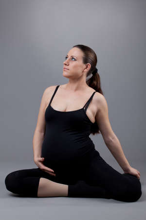Pregnant woman doing gymnastic exercises on grey background.の写真素材