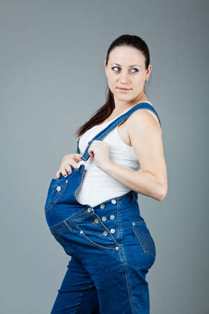 beautiful young pregnant woman in a dress with a gray backgroundの写真素材