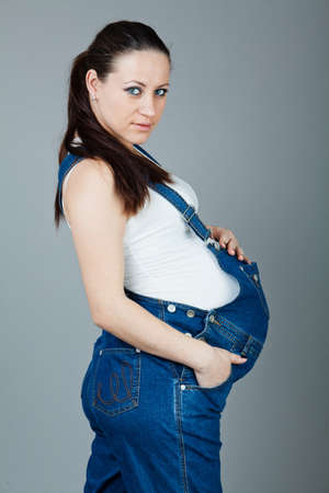 beautiful young pregnant woman in a dress with a gray backgroundの写真素材