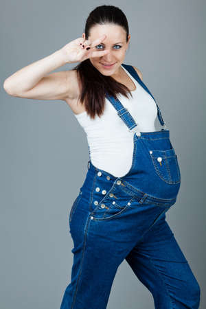 beautiful young pregnant woman in a dress with a gray backgroundの写真素材